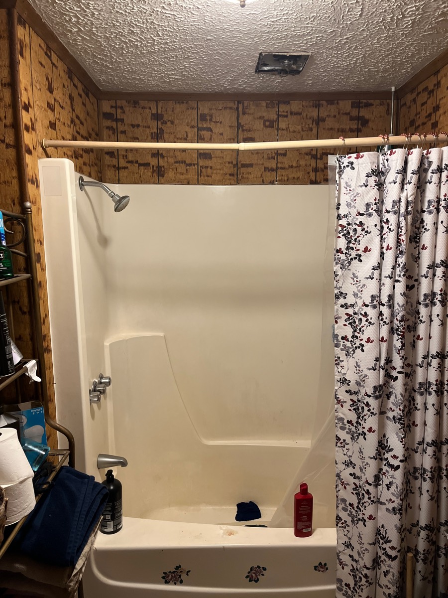 Bathroom before remodel — dated fiberglass tub and paneling