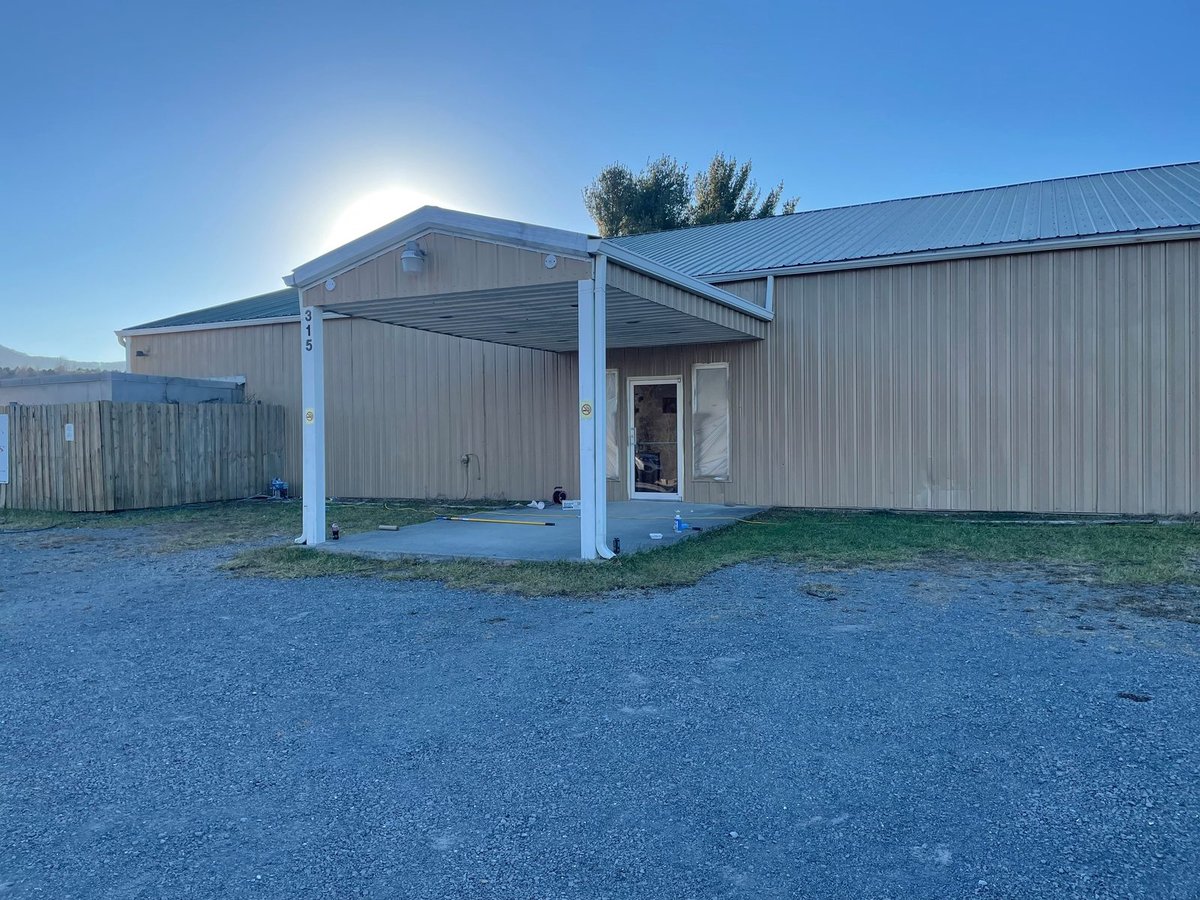 Metal building after — recoated siding with a finished entry canopy