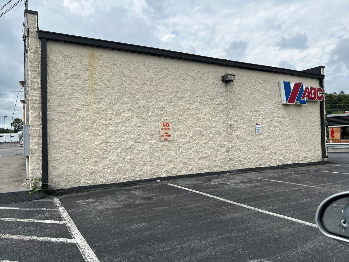 Store side wall before repaint — tan stucco and split-face block